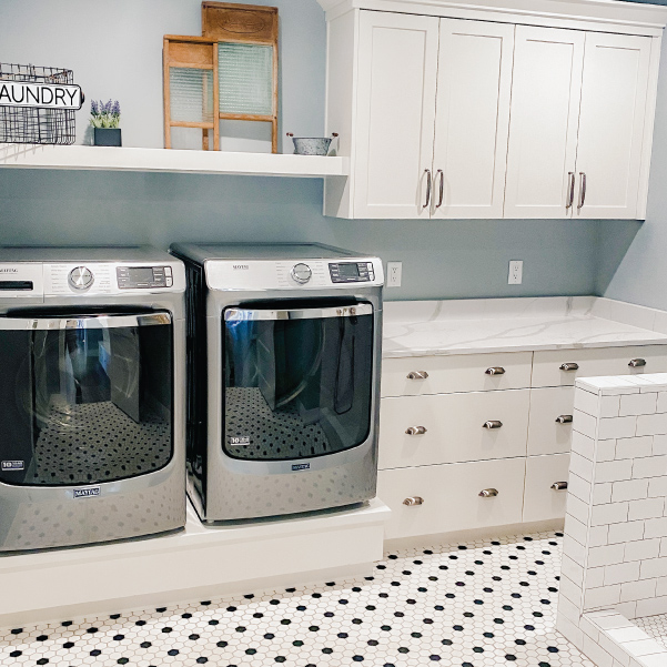 A white farmhouse laundry room with a stainless steel washer and dryer A white farmhouse laundry room with a stainless steel washer and dryer