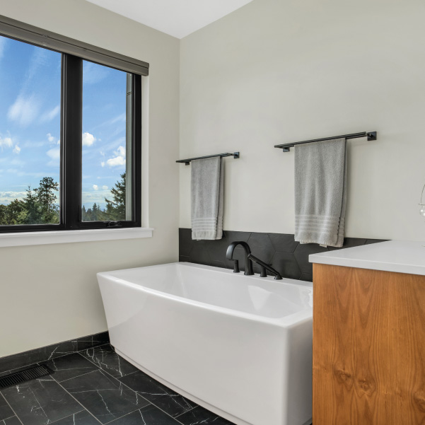 Striking white-and-black bathroom featuring a full tub in a modern home built by Riddle Construction Striking white-and-black bathroom featuring a full tub in a modern home built by Riddle Construction