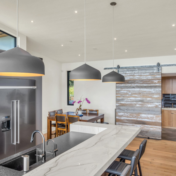 Sliding barn door and marble sit-up kitchen island in a modern kitchen built by Riddle Construction Sliding barn door and marble sit-up kitchen island in a built by Riddle Construction
