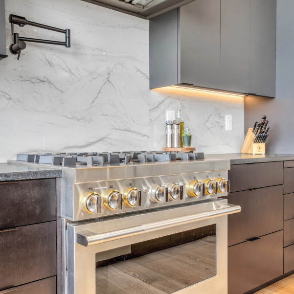 A stainless steel stove in a kitchen with a marble backsplash and mixed color countertops built by Riddle Construction A stainless steel stove in a kitchen with a marble backsplash and mixed color countertops built by Riddle Construction