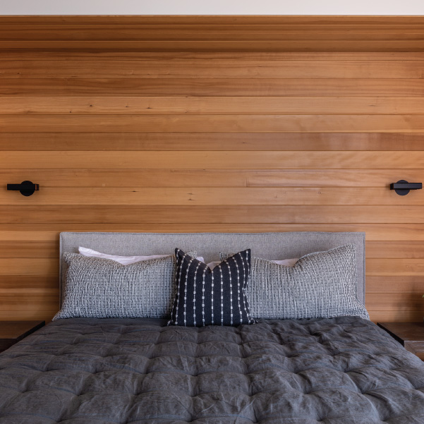 A bed with pillows in front of horizontal paneled wall with scones A bed with pillows in front of horizontal paneled wall with scones