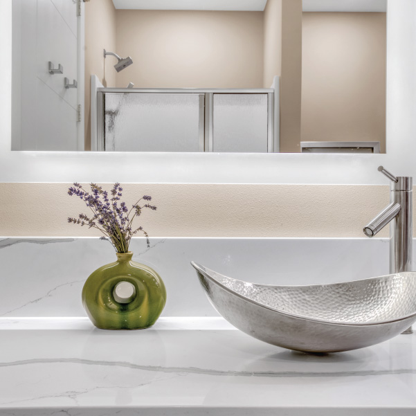 Silver metallic sink on a marble countertop under mirror with reflection of a modern shower Silver metallic sink on a marble countertop under mirror with reflection of a modern shower