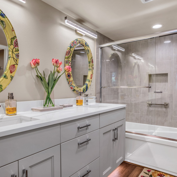 Double vanity with floral framed mirrors along full-sized bath and shower Double vanity with floral framed mirrors along full-sized bath and shower