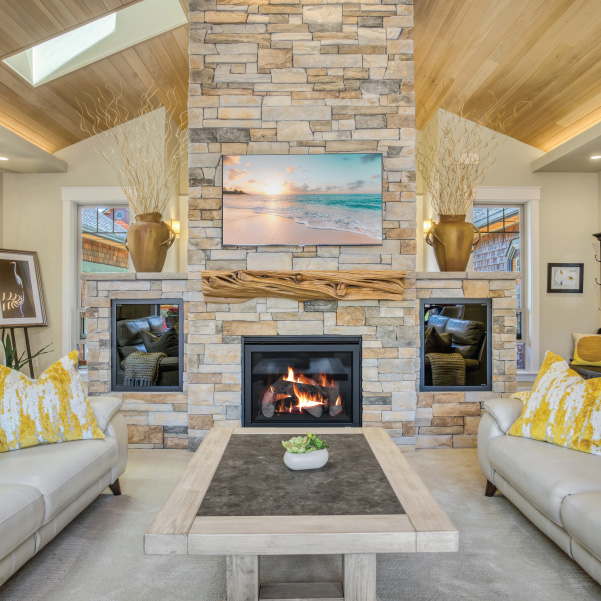 A flooring-to-ceiling fireplace with a mounted painting and wood mantle in a custom home built by Riddle Construction A flooring-to-ceiling fireplace with a mounted painting and wood mantle in a custom home built by Riddle Construction