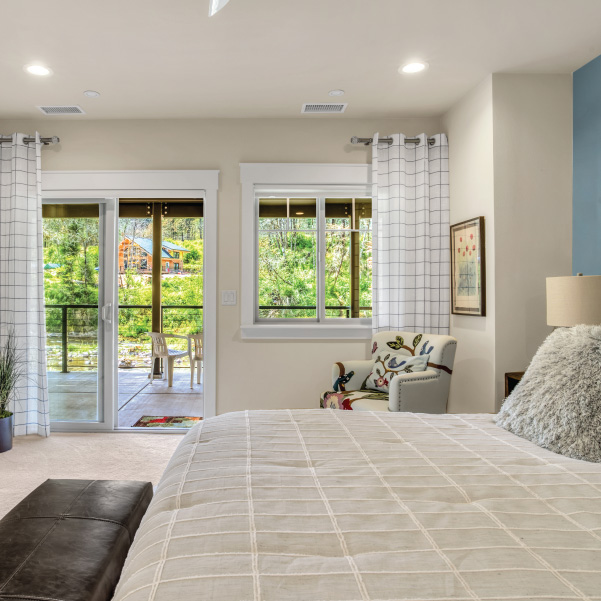 White bedroom with a sliding door leading out to patio area White bedroom with a sliding door leading out to patio area