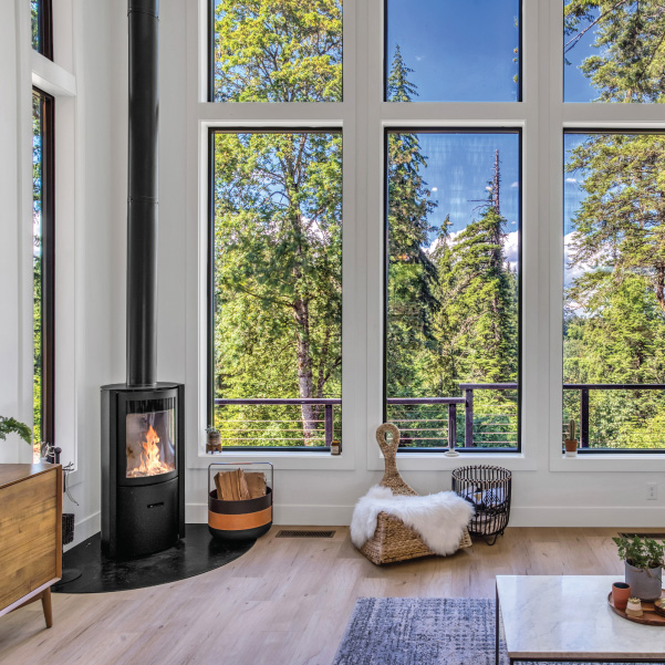 Freestanding wood stove next to tall vertical windows in a custom home built by Riddle Construction Freestanding wood stove next to tall vertical windows in a custom home built by Riddle Construction