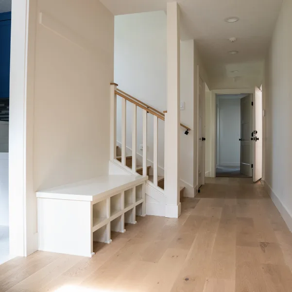Look down a hallway with a shoe cubby bench at the base of a stairway Look down a hallway with a shoe cubby bench at the base of a stairway