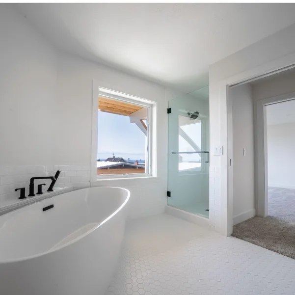 White soaking tub with walk-in shower with large square window with an ocean view White soaking tub with walk-in shower with large square window with an ocean view