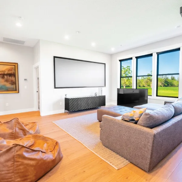 A comfortable media room with couch facing large television mounted on a wall A comfortable media room with couch facing large television mounted on a wall